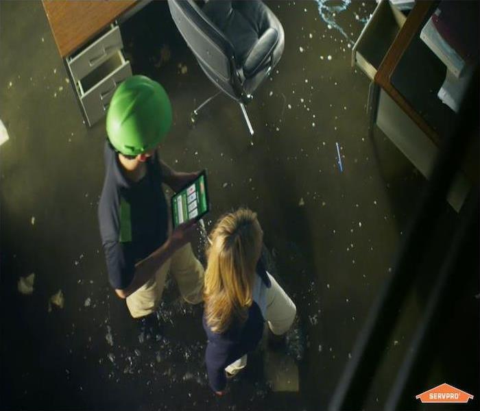 flooded office building with SERVPRO  technicians walking through