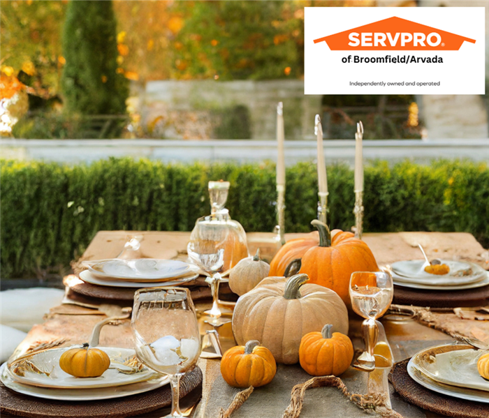 A table set up outside with an orange pumpkin, white candles, plates and cups