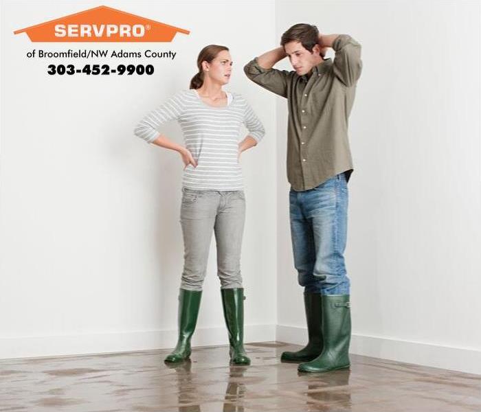 Man and woman standing on a wet floor wearing rain boots.